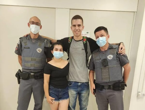 PM salva bebê em São José dos Campos; foto mostra os agentes policiais fardados ao lado da mãe e pai, em frente a uma parede branca.