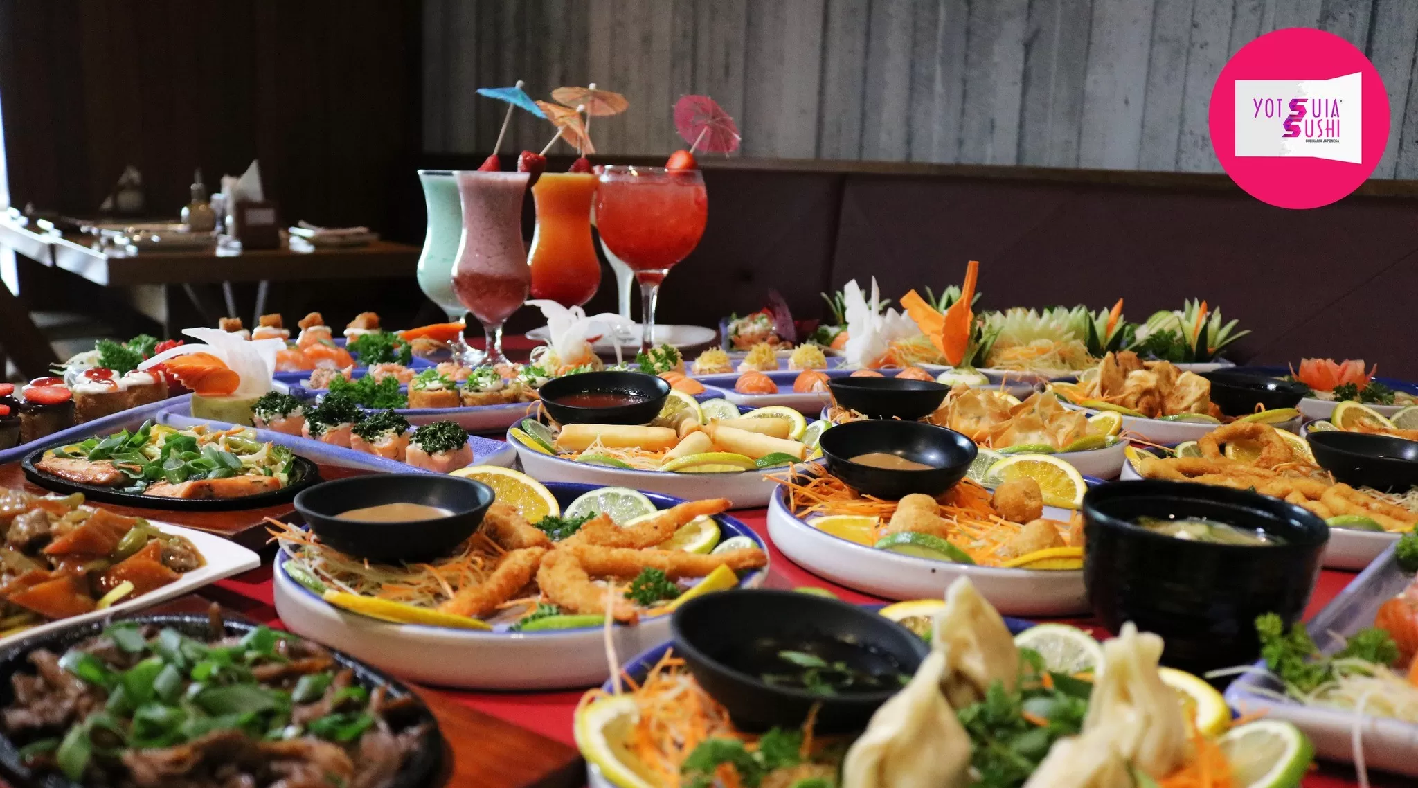 Mesa cheia das opções de rodízio: camarões empanados, drinks variados, shimeji, guioza, yakisoba, rolinho primavera e pratos frios, como sushis e sashimis