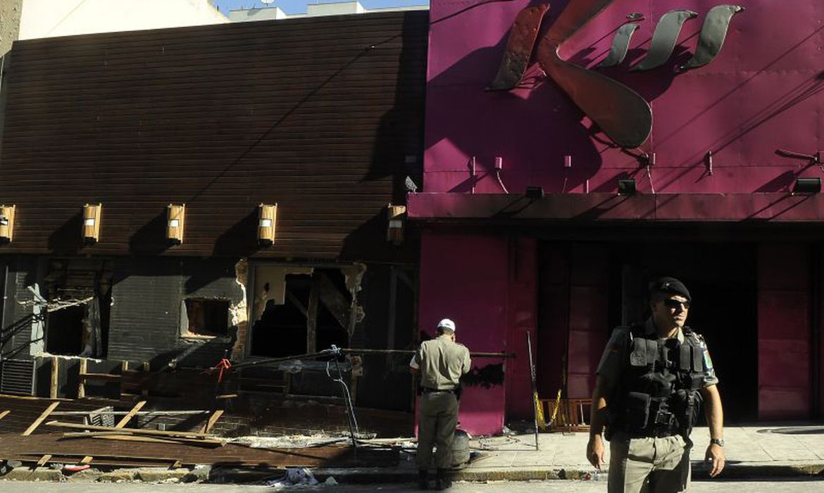 O julgamento de quatro réus pelo crime de homicídio no incêndio da Boate Kiss em Santa Maria (RS), em janeiro de 2013, entrou hoje (5) no quinto dia. Neste domingo estão previstos os depoimentos de Thiago Mutti, testemunha de defesa de um dos réus, e de uma das vítimas, Delvani Brondani Rosso . No sábado, Cristiane dos Santos Clavé, que estava no estabelecimento e perdeu 15 amigos naquela noite, prestou depoimento. Ela disse que estava de frente para o palco e viu dois fogos de artifício presos no chão durante o show da Banda Gurizada Fandangueira. Ao ver fumaça sentiu uma falta de ar muito forte e saiu do local para respirar melhor, desviando de várias pessoas que começaram a correr e a se empurrar. “A fumaça se espalhou rápido e chegou primeiro que eu lá na frente. Estava muito quente, era como o vapor de uma panela”, destacou. Por estar próxima à porta de saída, conseguiu deixar a boate. “Parecia uma cena de horror”, disse sobre o cenário já de fora da boate. “Passava por cima dos corpos”, lembrou. Sobre o amigo Leandro, (de apelido Chupa), que morreu no dia e foi encontrado próximo ao banheiro, ela afirmou que “tenho certeza que ele achou que ali era a saída”. Ao ser perguntada pelo juiz sobre o sentimento ao prestar depoimento e reviver os fatos, Cristiane disse que fazia isso em memória dos amigos falecidos. Conforme Christiane, a boate não tinha sinalização e não foi anunciado o incêndio. Ela ouviu ainda pessoas sendo barradas na saída da Kiss. “Eu tenho certeza de que muita gente morreu sem saber o que estava acontecendo”. São réus no processo Elissandro Callegaro Spohr e Mauro Londero Hoffmann, proprietários do estabelecimento, o vocalista da banda Marcelo de Jesus dos Santos, e o produtor musical Luciano Bonilha Leão. Entenda A tragédia, que matou 242 pessoas e deixou 636 feridas, começou no palco, onde se apresentava a Banda Gurizada Fandangueira, e logo se alastrou, provocando muita fumaça tóxica. Um dos integrantes disparou um artefato pirotécnico, atingindo parte do teto do prédio, que pegou fogo. A tragédia, que matou principalmente jovens, marcou a cidade de Santa Maria e abalou todo o país, pelo grande número de mortos e pelas imagens fortes. A boate tinha apenas uma porta de saída desobstruída. Bombeiros e populares tentavam, de todo jeito, abrir passagens quebrando os muros da casa, mas a demora no socorro acabou sendo trágica para os frequentadores. Após a tragédia, normas para prevenção de incêndio em estabelecimentos similares foram alteradas para garantir maior segurança em todo o Brasil. A maior parte acabou morrendo pela inalação de fumaça tóxica, do isolamento acústico do teto, formado por uma espuma inflamável, incompatível com as normas de segurança modernas. Desde o incêndio, as famílias dos jovens mortos formaram uma associação e, todos os anos, no dia 27 de janeiro, relembram a tragédia, a maior do estado do Rio Grande do Sul e uma das maiores do Brasil.