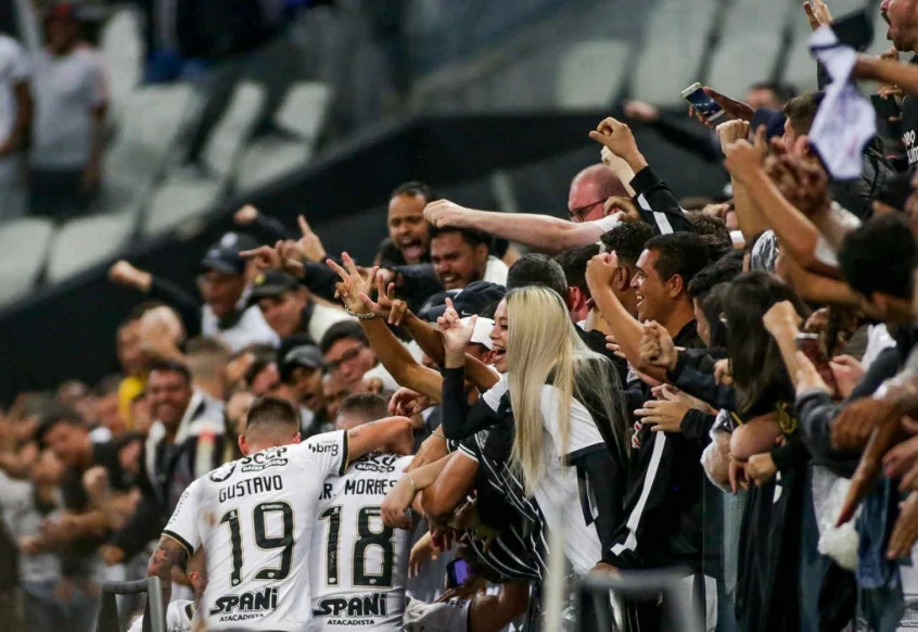 Torcida do Corinthians no estádio, com jogadores e torcedores vestindo a camisa.