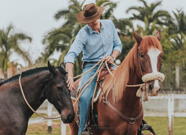 Ulysses Ervilha, Rancho Experientia Equus de Caçapava, montando em um cavalo e passando a mão em outro.