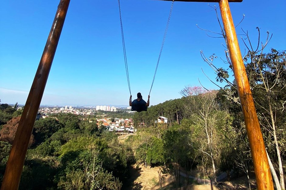 Estrutura do balanço infinito do Parque Alberto Simões, localizado em São José dos Campos, com uma pessoa balançando e o céu azul ao fundo.