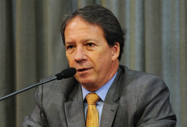 Edson Aparecido. Ele possui cabelo liso, preto com tons de grisalho, repartido ao meio.