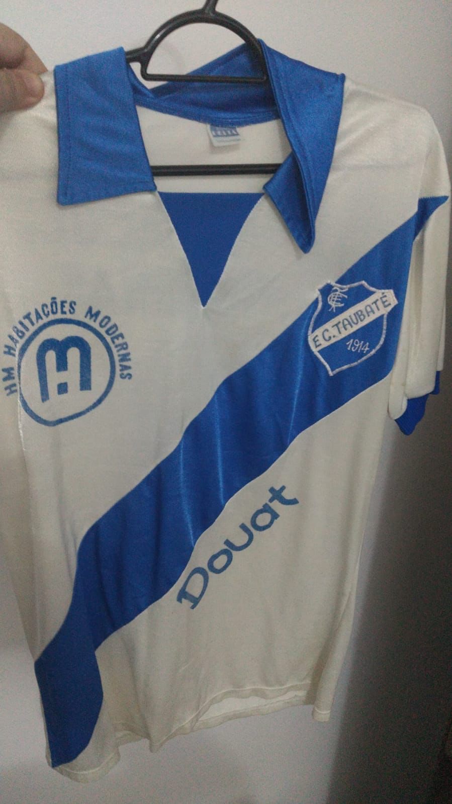Camisa do Burrão branca com faixa na diagonal azul, gola azul e manga azul e patrocínio da Douat