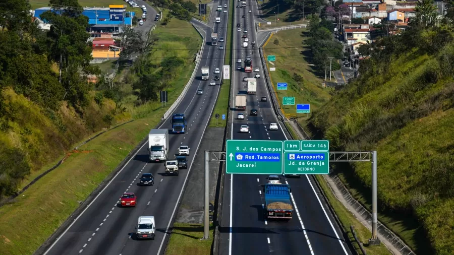 Rodovia Presidente Dutra, trecho de SJC, com duas estradas no meio, placas verdes e a natureza ao lado.