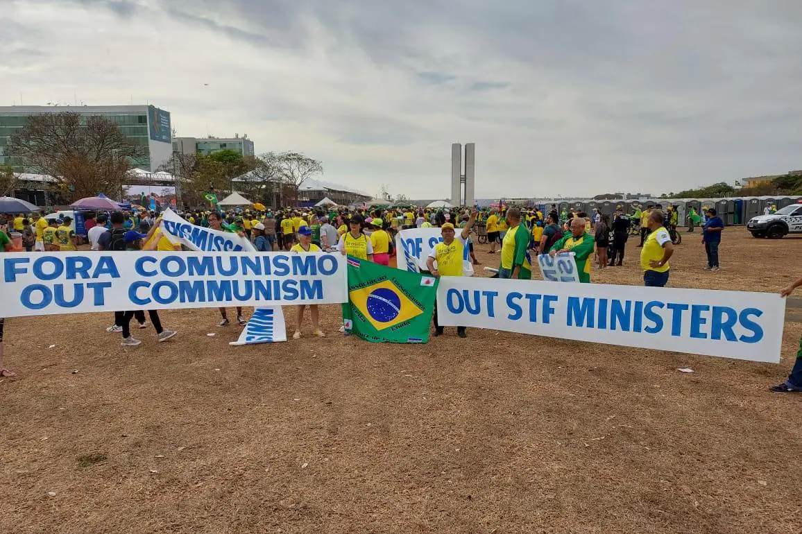 Manifestantes com a camisa do Brasil levantando um cartaz neste 7 de setembro em prol do fim do comunismo.
