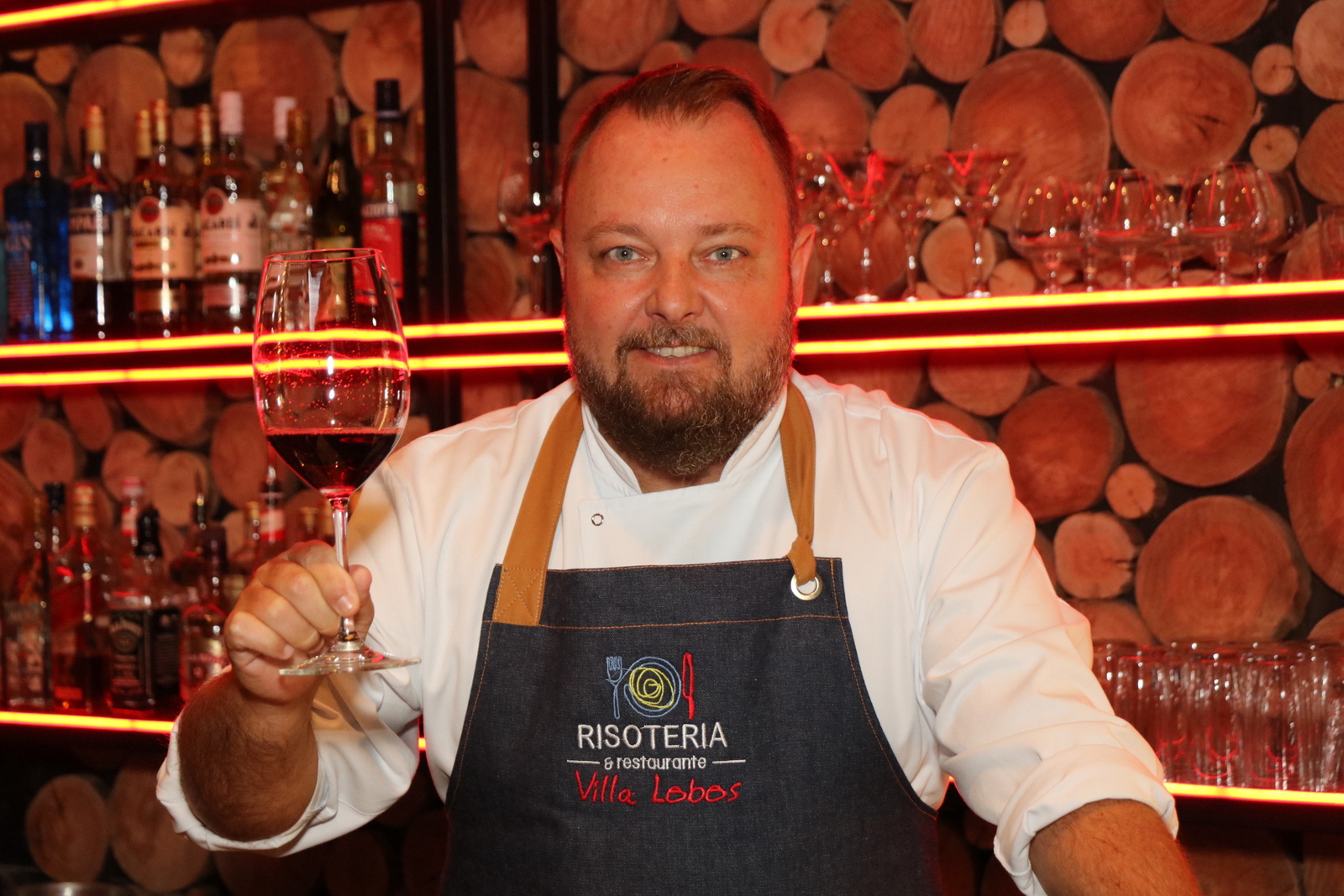 Chef Tercio Raddatz com uma taça de vinho na mão.
