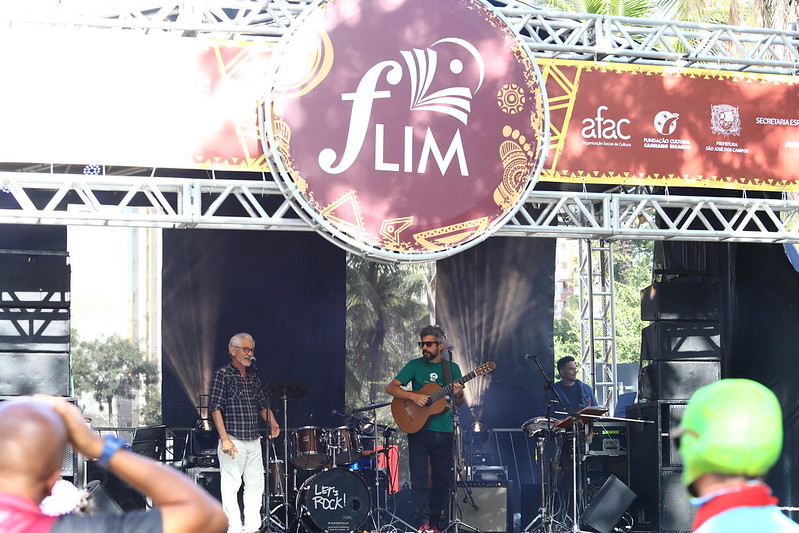 Fachada d FLIM, no Parque Vicentina Aranha, edição 2022, com pessoas tocando instrumentos no palco, e algumas pessoas olhando.