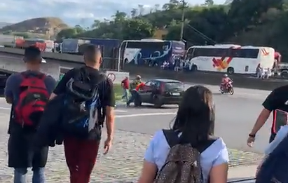 Frame do vídeo que mostra caminhoneiros atacando carro com adesivo de Lula na Via Dutra, com pessoas em volta olhando.