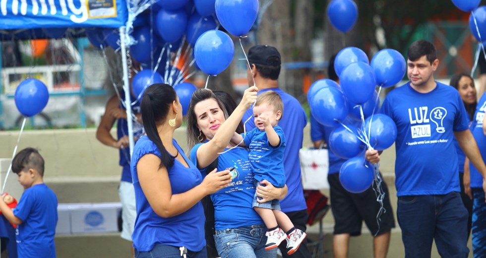 Evento Blue Day em SJC, para crianças autistas, com diversas pessoas usando roupa azul e segurando balões.