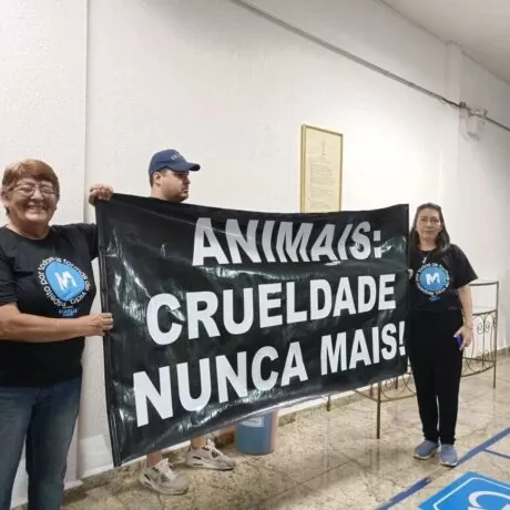 Integrantes do Instituto Marilu Godoi, com roupas pretas, segurando uma placa com manifestação contra os rodeios em Taubaté.