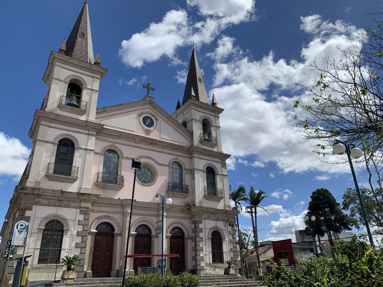 Fachada da Igreja Matriz de Jacareí, com céu azul, árvore ao lado, poste na frente e área verde.