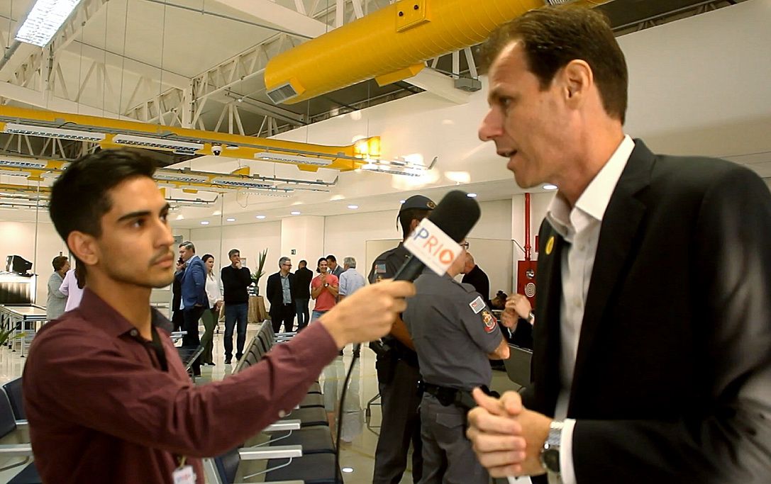 Ronei Saggioro Glanzmann durante entrevista ao jornalista Matheus Andrade, da SP RIO+, falando no microfone, o evento de concessão à iniciativa privada do aeroporto de SJC.