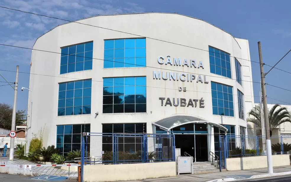 Fachada da Câmara de Taubaté, com vidros na frente, céu azul e portão de grade; foto ilustra matéria sobre projeto de lei do prefeito José Saud sobre negociação de dívidas e multas.