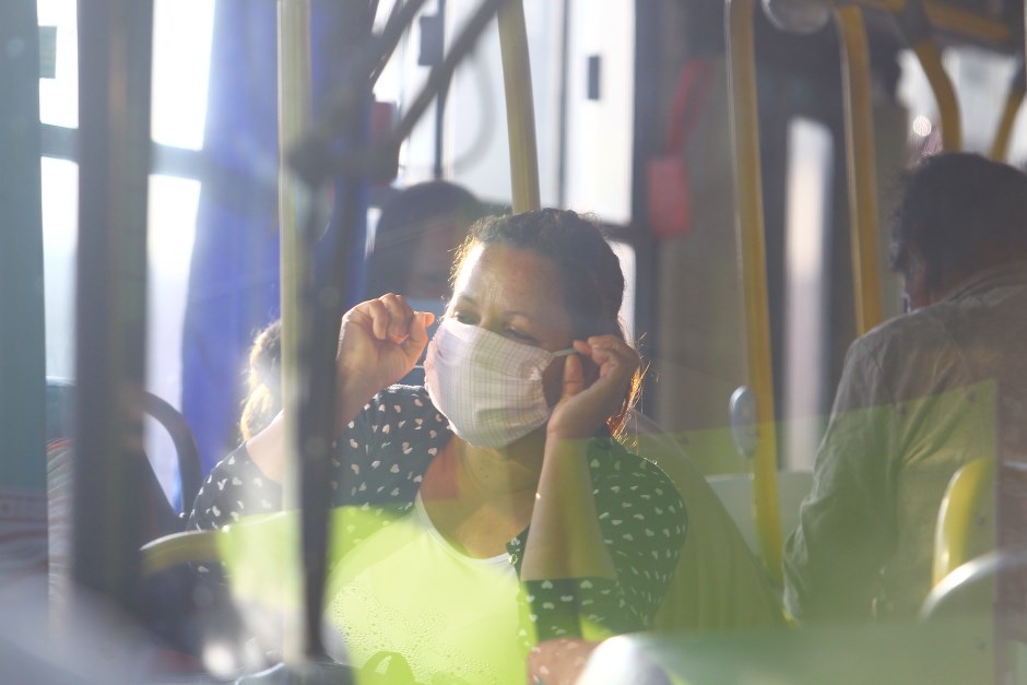 Mulher com máscara no transporte público de São José dos Campos, com roupa amarela e blusa preta com bolinhas.