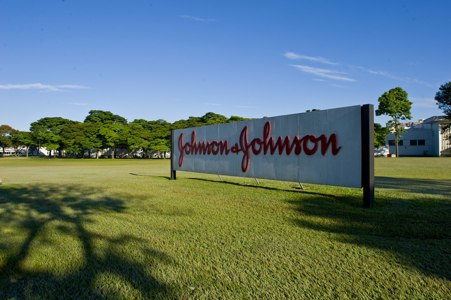 Emprego na Johnson&Johnson: empresa divulga vagas no site oficial; foto mostra placa da marca, em branco e vermelho, em cima de um gramado verde e céu azul.