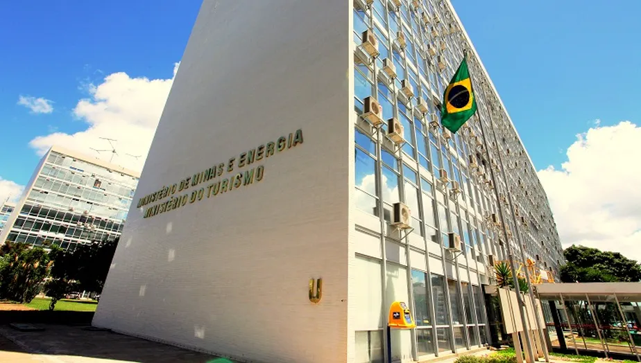 Ministério do Turismo rebate relatório do governo de transição do Lula; foto mostra a fachada da pasta, céu azul, bandeira do Brasil e vidros.