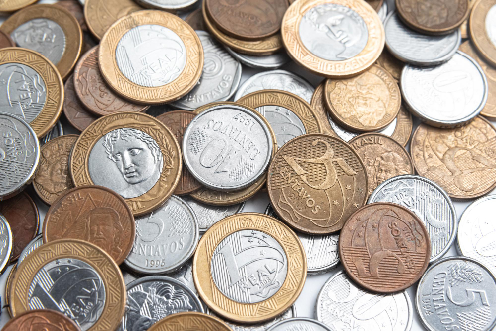 Moedas brasileiras espalhadas e em cima umas das outras; foto ilustra a matéria sobre o pagamento do 13º salário.