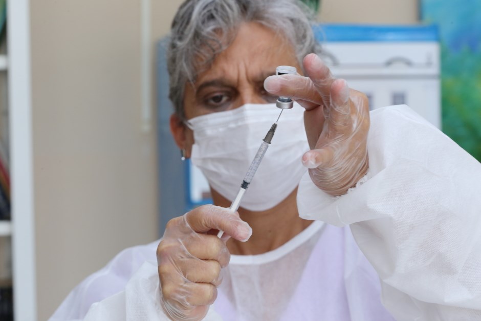 Mulher com roupas brancas, luva e máscara, segurando uma vacina da Pfizer Baby, contra a covid, em um hospital. Foto Adenir Britto-PMSJC