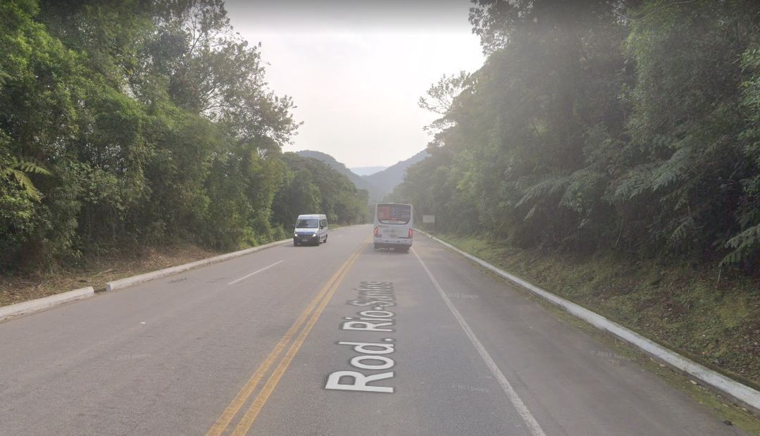Trecho da Rodovia Rio-Santos que será interditado, na região da Picinguaba, com área verde em volta, estrada, carros passando e listra amarela no meio.