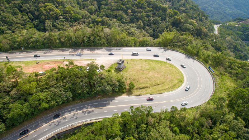 Serra antiga da Rodovia dos Tamoios, com área verde em volta, carros na pista e uma curva.