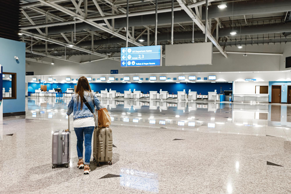 Mulher com malas andando em direção aos guichês de um aeroporto; foto ilustra a matéria sobre a greve nos aeroportos.