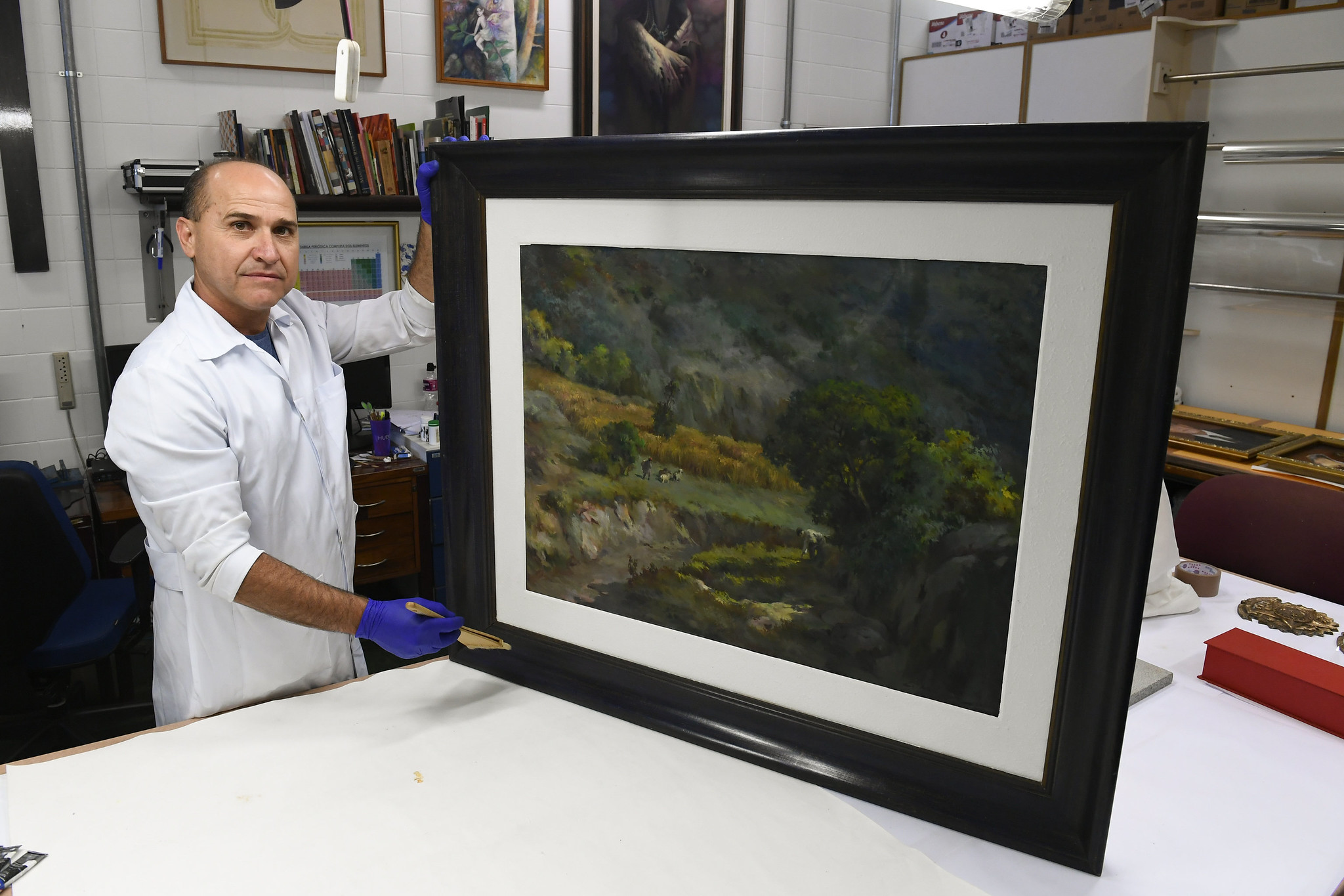 restaurador Nonato Nascimento segurando obra "Trigal na Serra", de Guido Mondin, primeira obra a ser restaurada e voltar a ser exposta pelo senado após atos golpistas em 8 de janeiro, em brasília