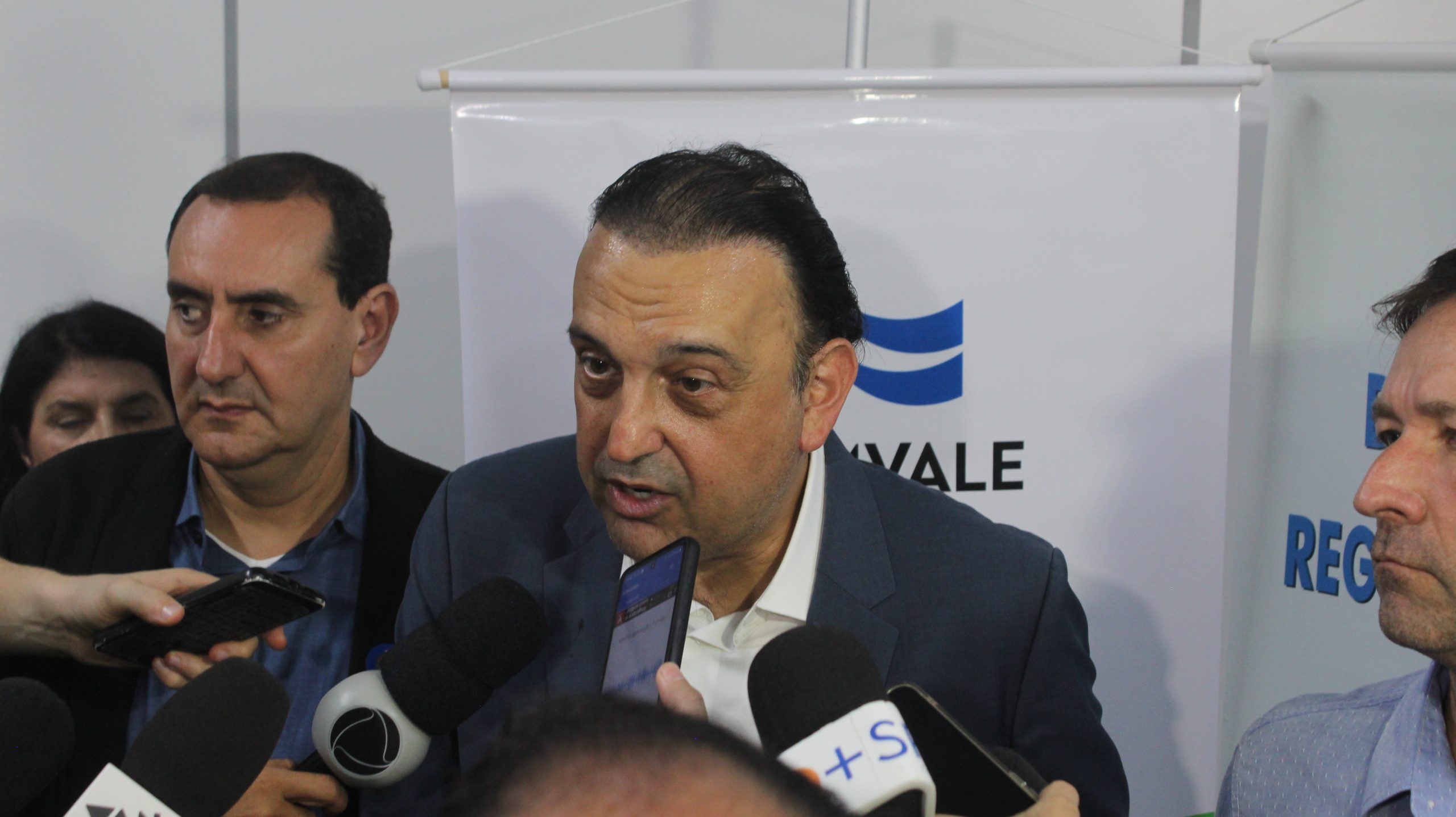 Felicio Ramuth sendo entrevistado por repórteres da imprensa após reunião da AGEMVALE. O vice-governador de São Paulo utiliza terno preto e camisa branca. Foto ilustra a matéria sobre os investimentos para resolver o desvio na Tamoios.