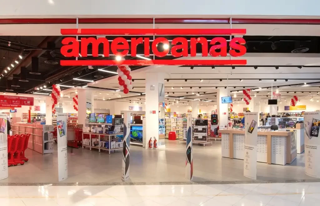 Fachada da Lojas Americanas, com uma placa em cima, entrada aberta e produtos à venda.
