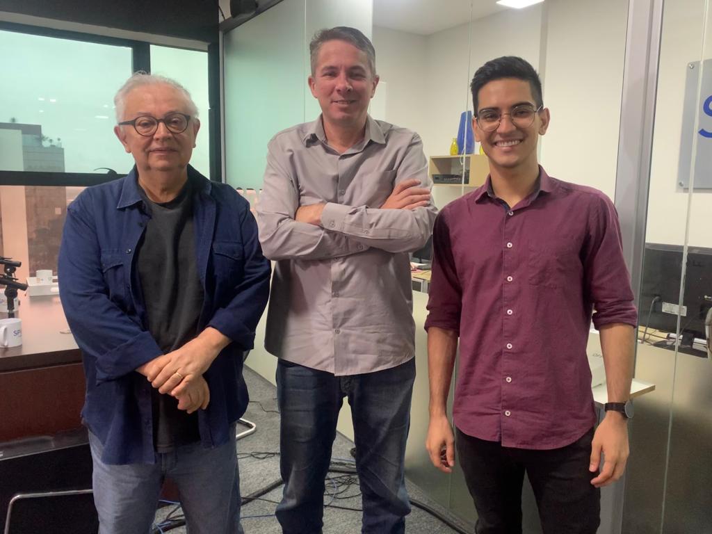 Jornalista Matheus Andrade, jornalista José Guilherme Ferreira e vereador Alberto Barreto, de Taubaté, durante entrevista em São José dos Campos no estúdio do Portal SP RIO+; na foto os três estão um ao lado do outro, com um vidro atrás e a cidade na janela.