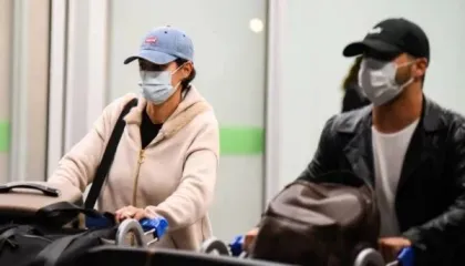 Michelle Bolsonaro retorna ao Brasil sem o ex-presidente Jair; na foto ela usa casaco rosa, boné e máscara.