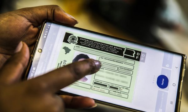 imagem de uma mão no celular, da pessoa fazendo o processo de renovação da CNH; foto ilustra matéria de renovação da CNH