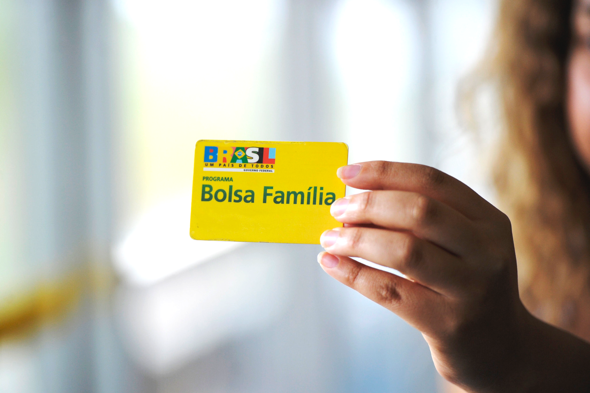 mão de mulher segurando cartão do bolsa família