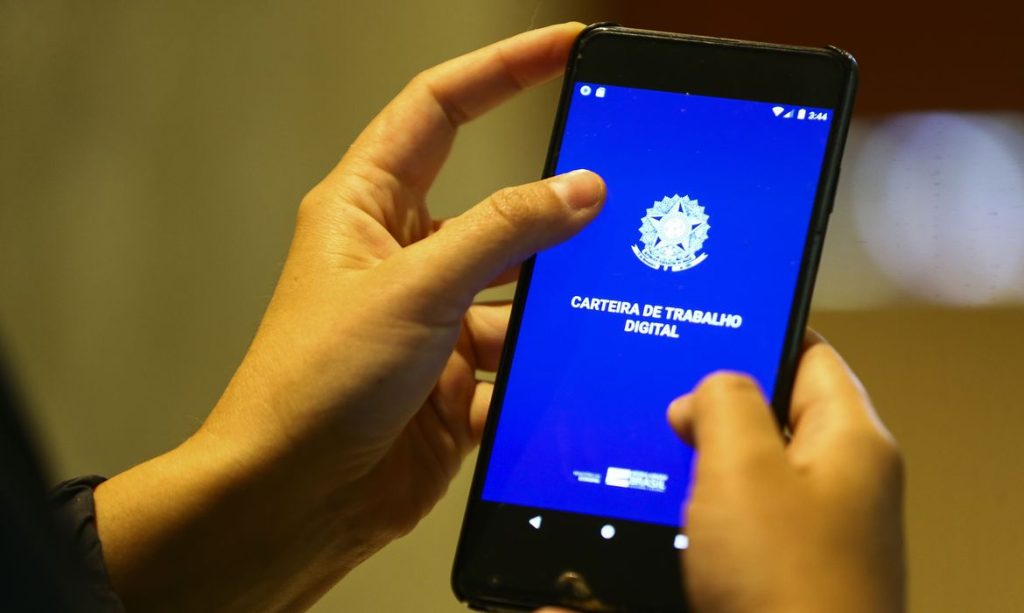 imagem de uma pessoa acessando no celular a Carteira de Trabalho Digital; foto ilustra matéria sobre empregados sem carteira assinada batem recorde em 2022