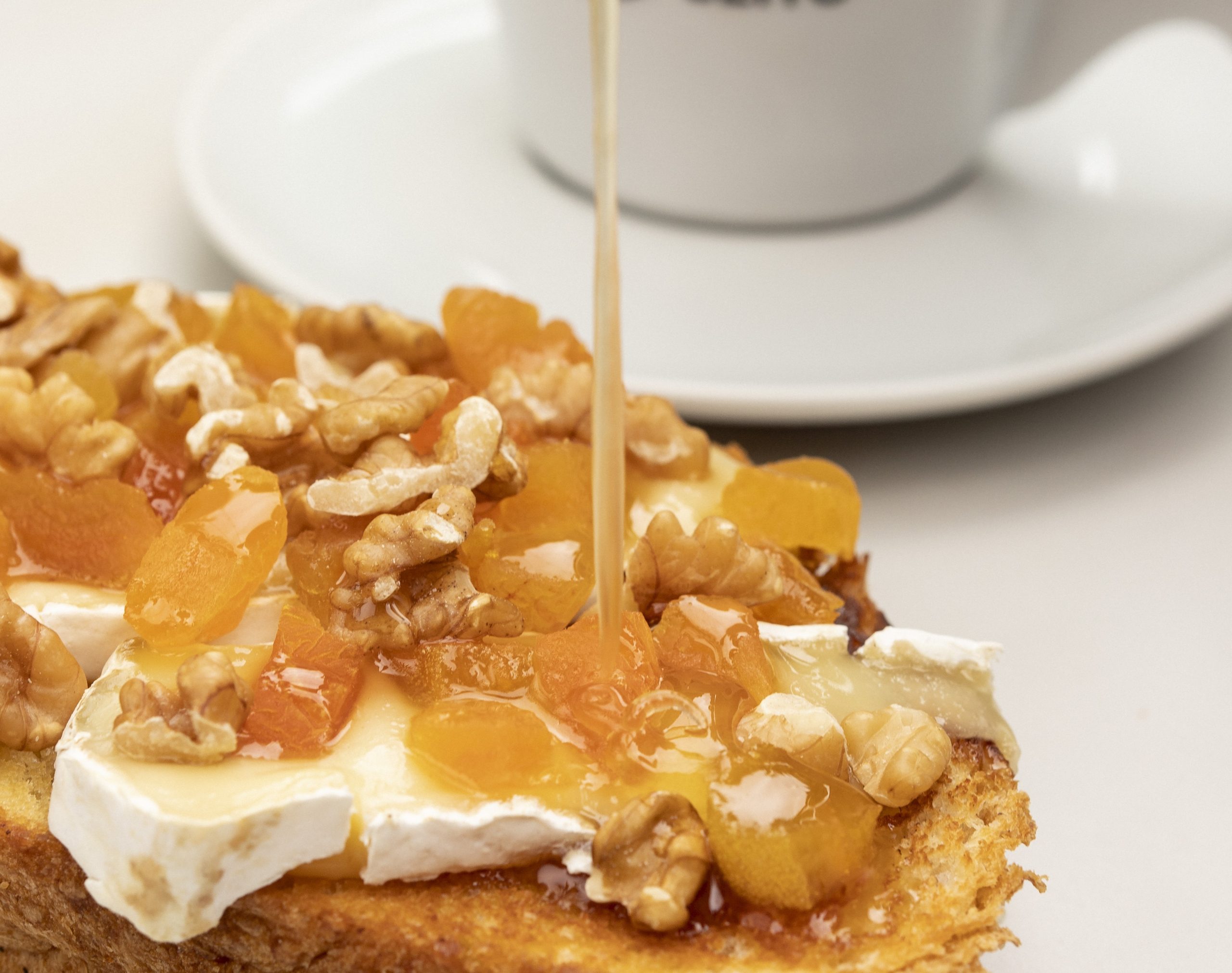 Foto mostra pão com cobertura doce em cima de uma mesa branca, com uma xícara ao fundo, ilustrando matéria sobre o novo Café Conceito, no Taubaté Shopping.
