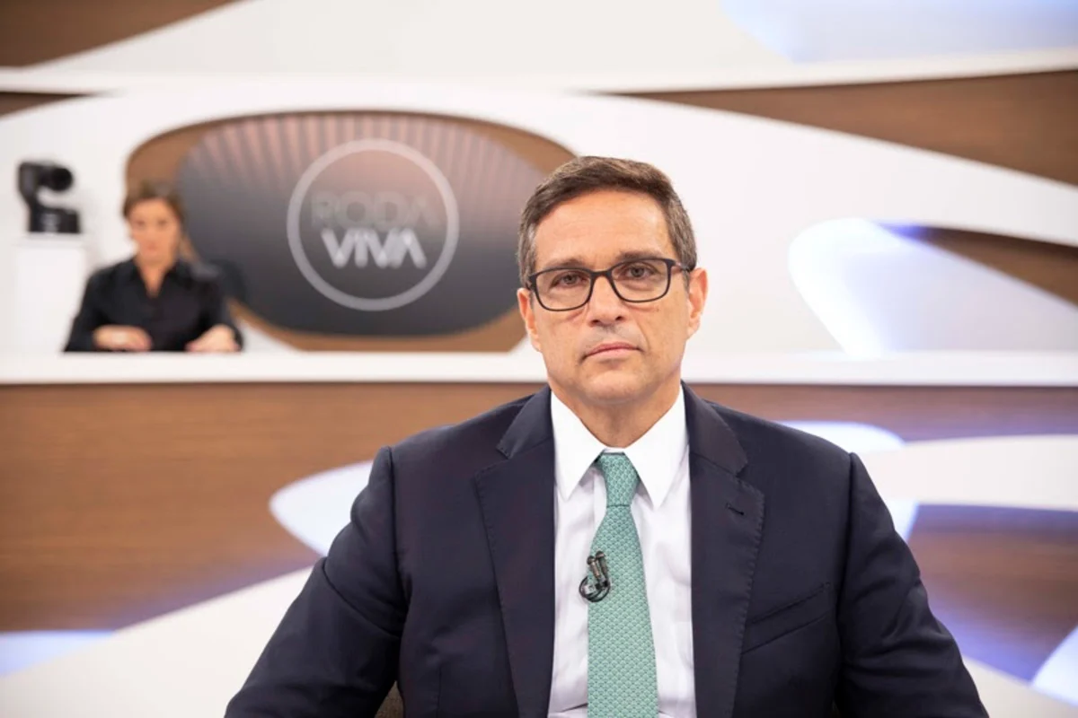 Campos Neto durante entrevista ao Roda Viva, da TV Cultura; na foto ele usa terno preto, camisa branca, gravata verde, está sentado em frente ao estúdio e a jornalista Vera Magalhães o observa ao fundo.