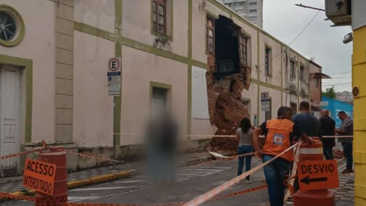 Parte lateral da Capela Nossa Senhora do Rosário, em Jacareí, em que uma parede cede. Foto mostra pessoas em volta do incidente.