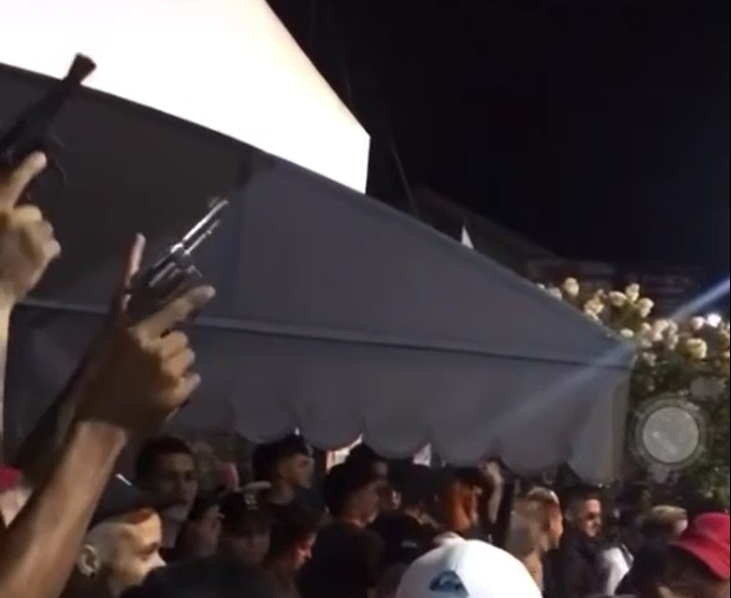 Carnaval em Pinda tem fluxo com criminosos levantando a arma durante um fluxo. Foto mostra multidão de pessoas em baixo e as armas no lado esquerdo.