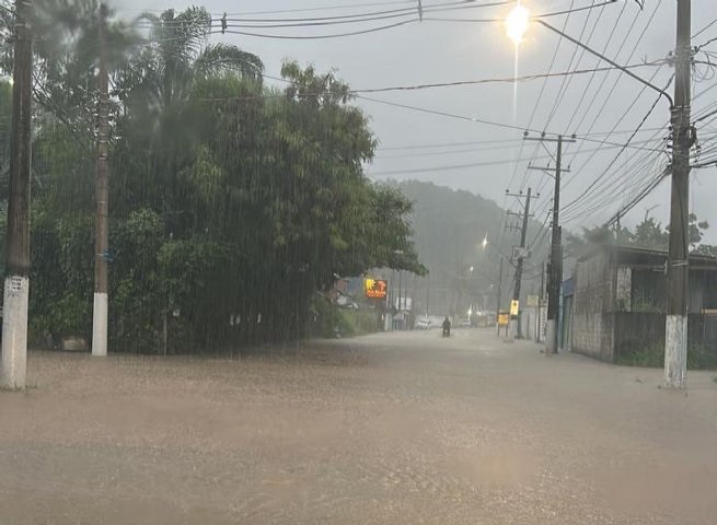 Foto mostra chuva em São Sebastião, com ruas alagadas; primeira morte foi confirmada pela Prefeitura. Chuvas atingiram o Litoral Norte de São Paulo no sábado (18).