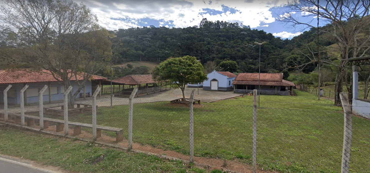 Vista externa da Igreja da Pedra Branca, em Cunha, com um céu azul em cima, área verde em volta e uma cerca.