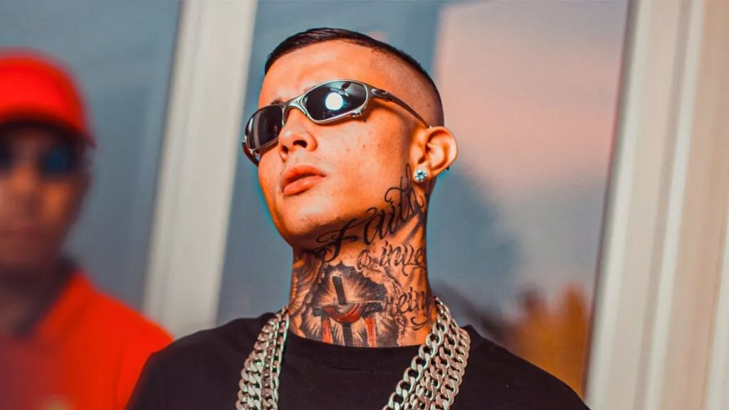 mc paiva, de são josé dos campos, em foto em primeiro plano. ele é branco, tatuado, usa correntes grossas de prata no pescoço e óculos escuros tipo juliet.