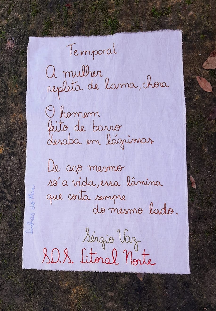 Poema do poeta Sérgio Vaz em homenagem às vítimas de São Sebastião, bordado na cor vermelha sob um pano branco.