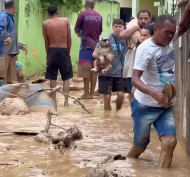 Foto mostra o resgate em São Sebastião dos moradores afetados pelas fortes chuvas que atingiram o Litoral Norte, com lama na parte de baixo e pessoas andando na parte direita da imagem.
