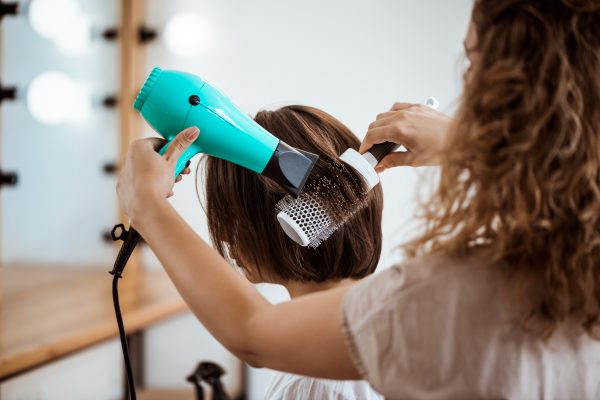 imagem de uma cabeleireira fazendo escova no cabelo de uma mulher; foto ilustra matéria sobre cursos de capacitação, ofertados pelo Sebrae-SP, em Taubaté.