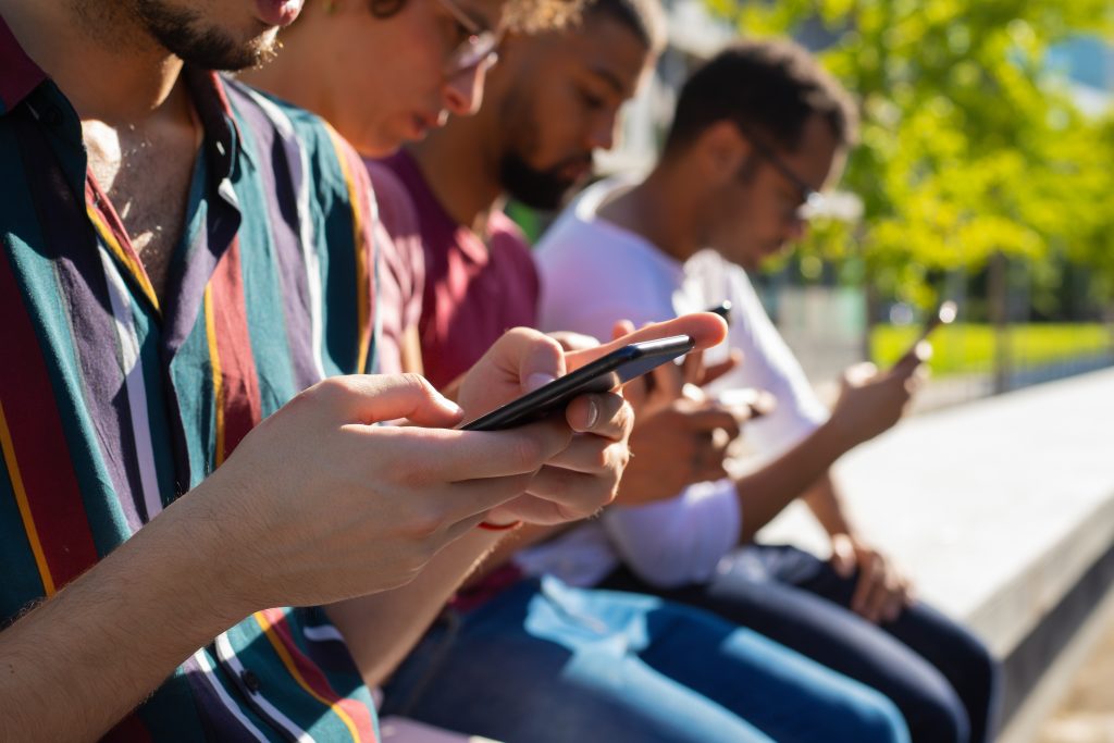 imagem de adolescentes mexendo no celular; foto ilustra matéria sobre Jovens que utilizam eletrônicos por mais de 3 horas ao dia têm dor na coluna