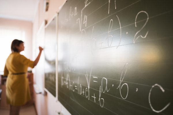 imagem de uma professora escrevendo na lousa; foto ilustra matéria sobre SP publica decreto de pagamento do piso salarial para professores