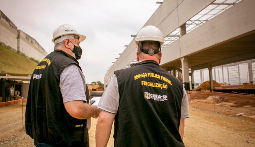 Agentes do CREA-SP, com roupa preta e chapéu branco, durante uma vistoria em uma construção civil; foto ilustra visita ao Vale Histórico.