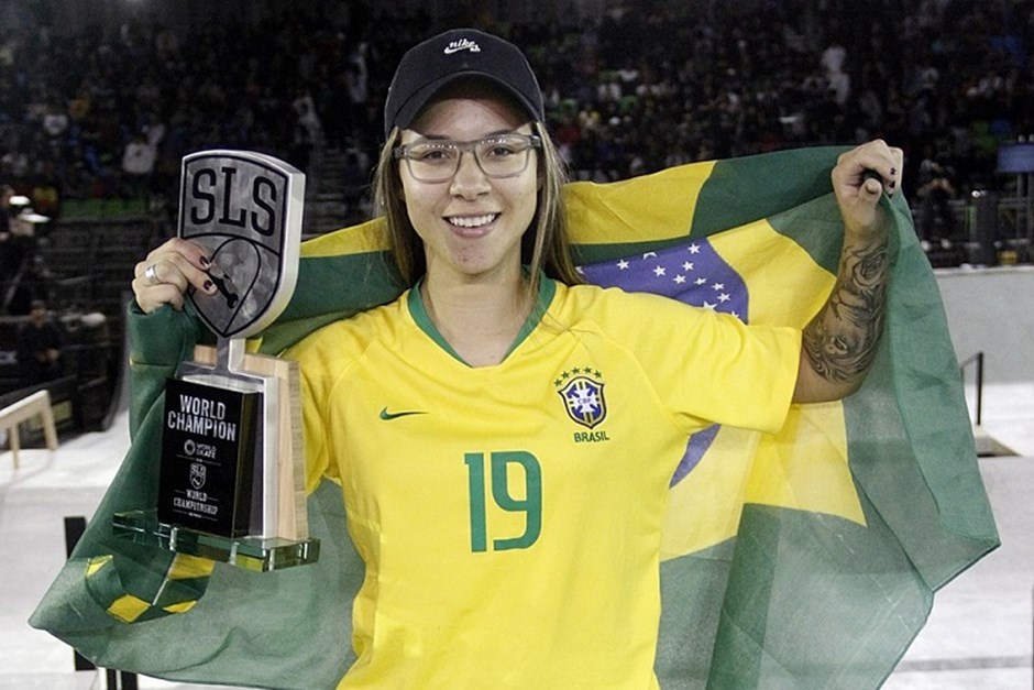 Pamela Rosa, skatista de São José dos Campos, com camisa da Seleção Brasileira, segurando um troféu, com boné preto, sorrindo e com óculos, ilustrando matéria sobre abertura dos Jogos Escolares 2023.