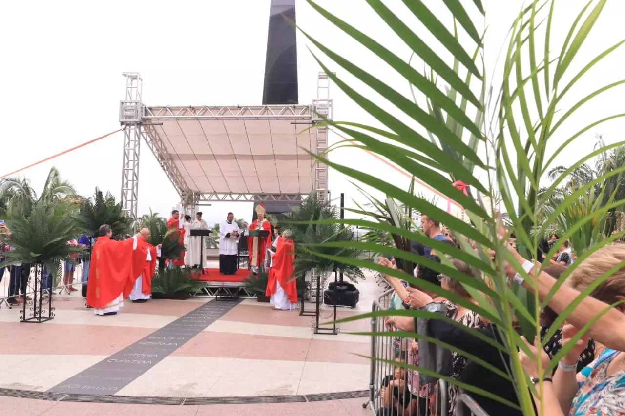 Santuário de Aparecida realiza celebração do Domingo de Ramos; foto mostra os religiosos com vestimentas vermelhas durante bênção dos ramos.