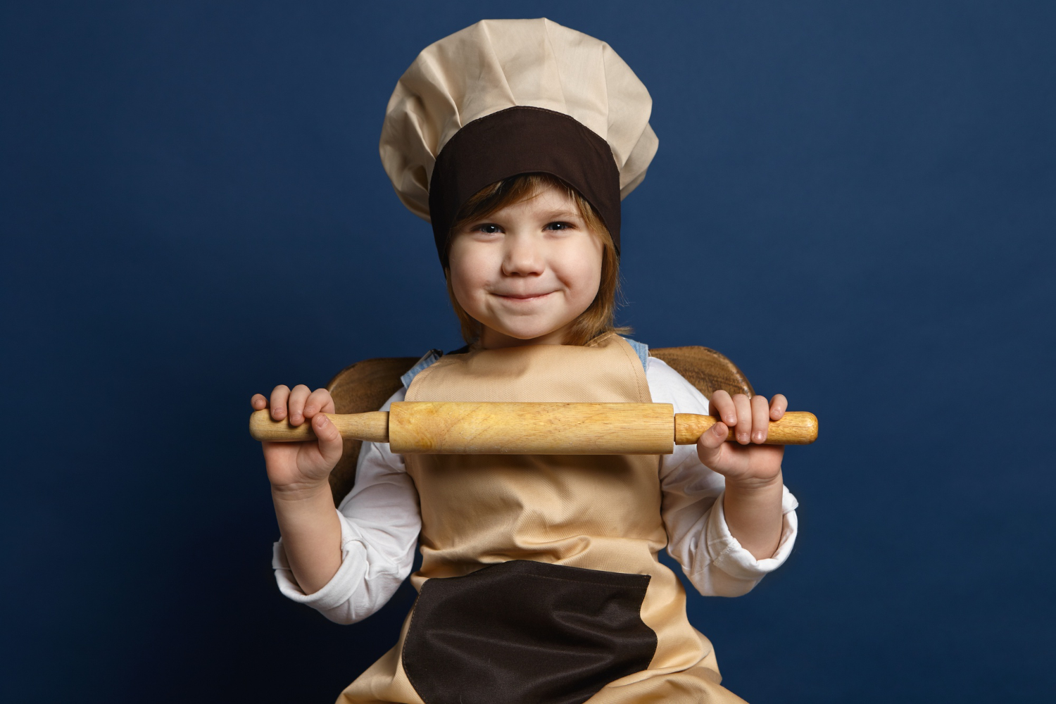 Garotinha com chapéu de cozinheiro, roupa e instrumentos à caráter, em frente a um fundo azul; foto ilustra matéria sobre festival +Gastronomia, em São José dos Campos (Parque Vicentina Aranha).